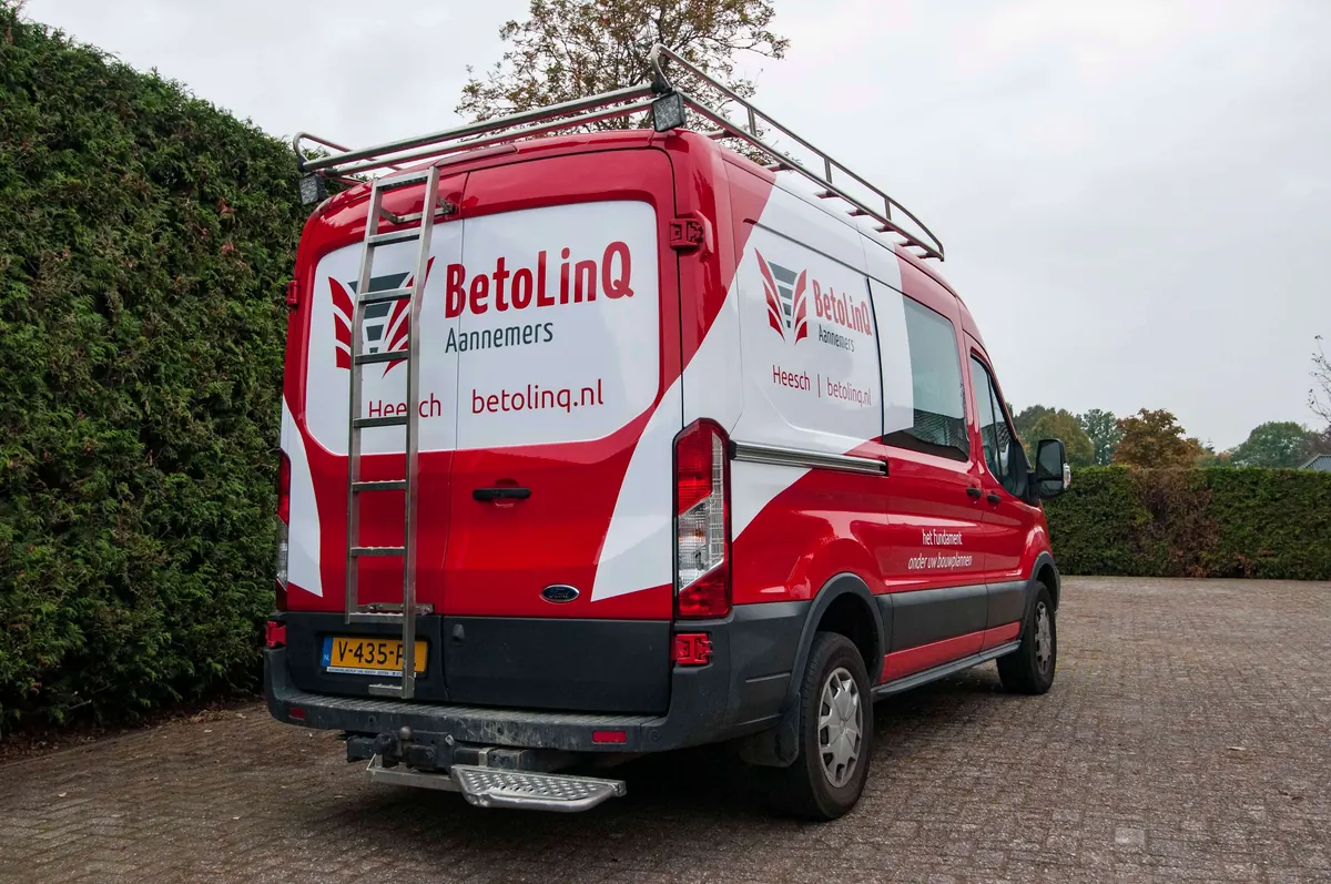 Bedrijfsbus van BetolinQ Aannemers met rode belettering