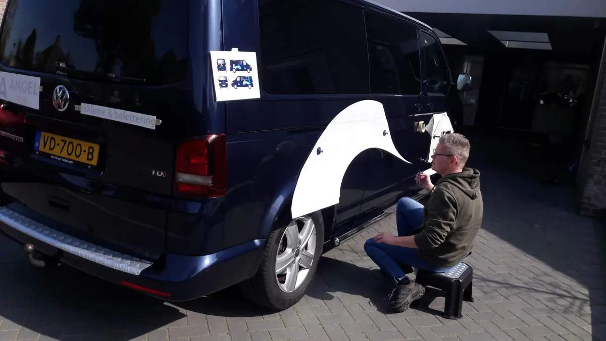 De lichtblauwe boog uit het logo wordt op de bus aangebracht